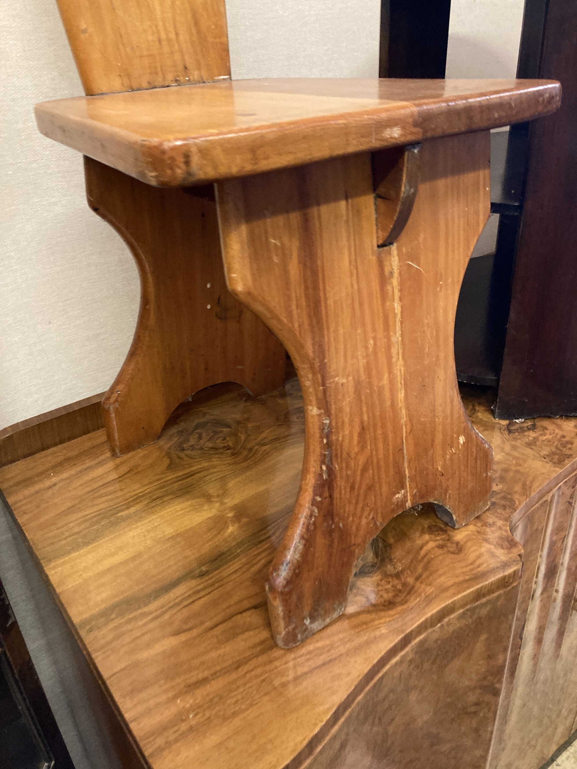 A pair of Italian style pitch pine hall chairs, stamped underneath R.Woolfe and J. Hadaway, width 38cm depth 50cm height 98cm